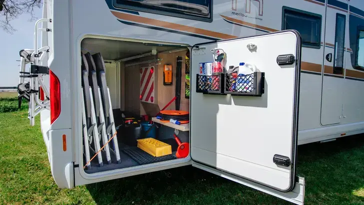 Wohnmobil-Heckgarage mit Campingmöbeln und gesichertem Reisegepäck.